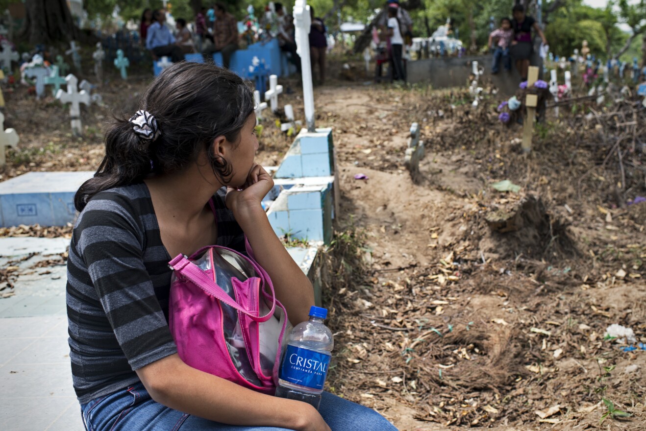 A girl observes her father's funeral at a local cemetery. Her father was one of the bus drivers killed during the ban imposed by gangs in San Salvador.